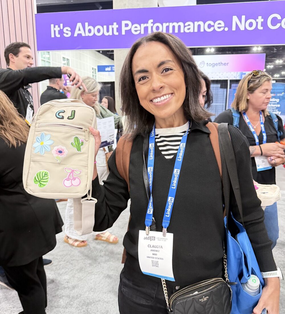 A guest at an event holds up a tan crossbody bag customized on site with stitched floral and cherry patches